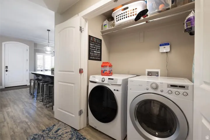Laundry area with light wood finished floors and washing machine and clothes dryer