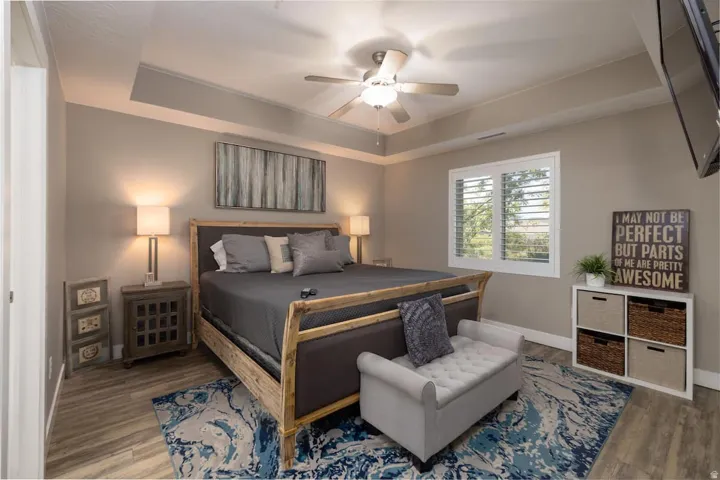 Master Bedroom featuring a tray ceiling, a ceiling fan, and wood finished floors