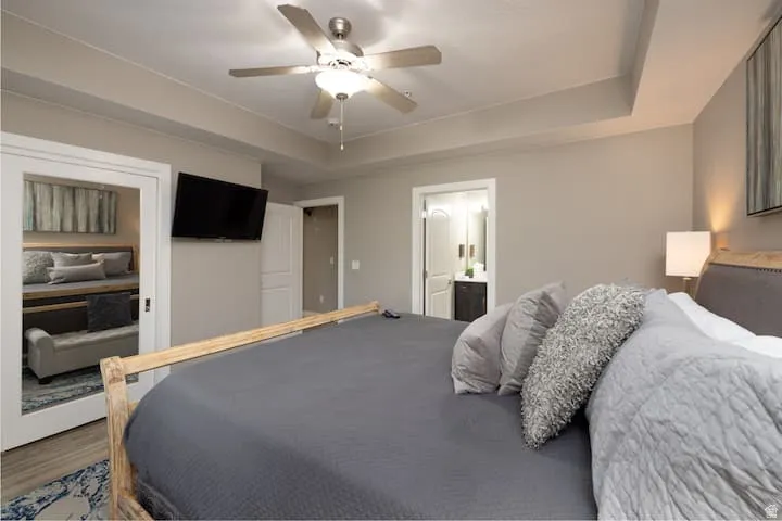 Master Bedroom featuring a raised ceiling, a ceiling fan, wood finished floors, and ensuite bathroom