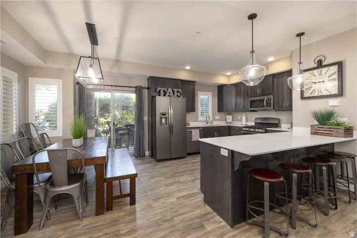 Kitchen with light countertops, stainless steel appliances, a peninsula, hanging light fixtures, and a breakfast bar