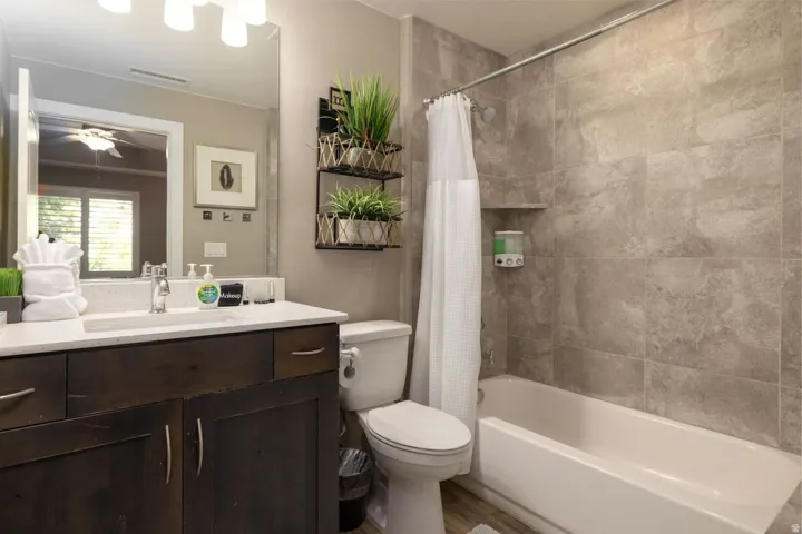 Full bath with vanity, shower / bath combo, ceiling fan, and wood finished floors