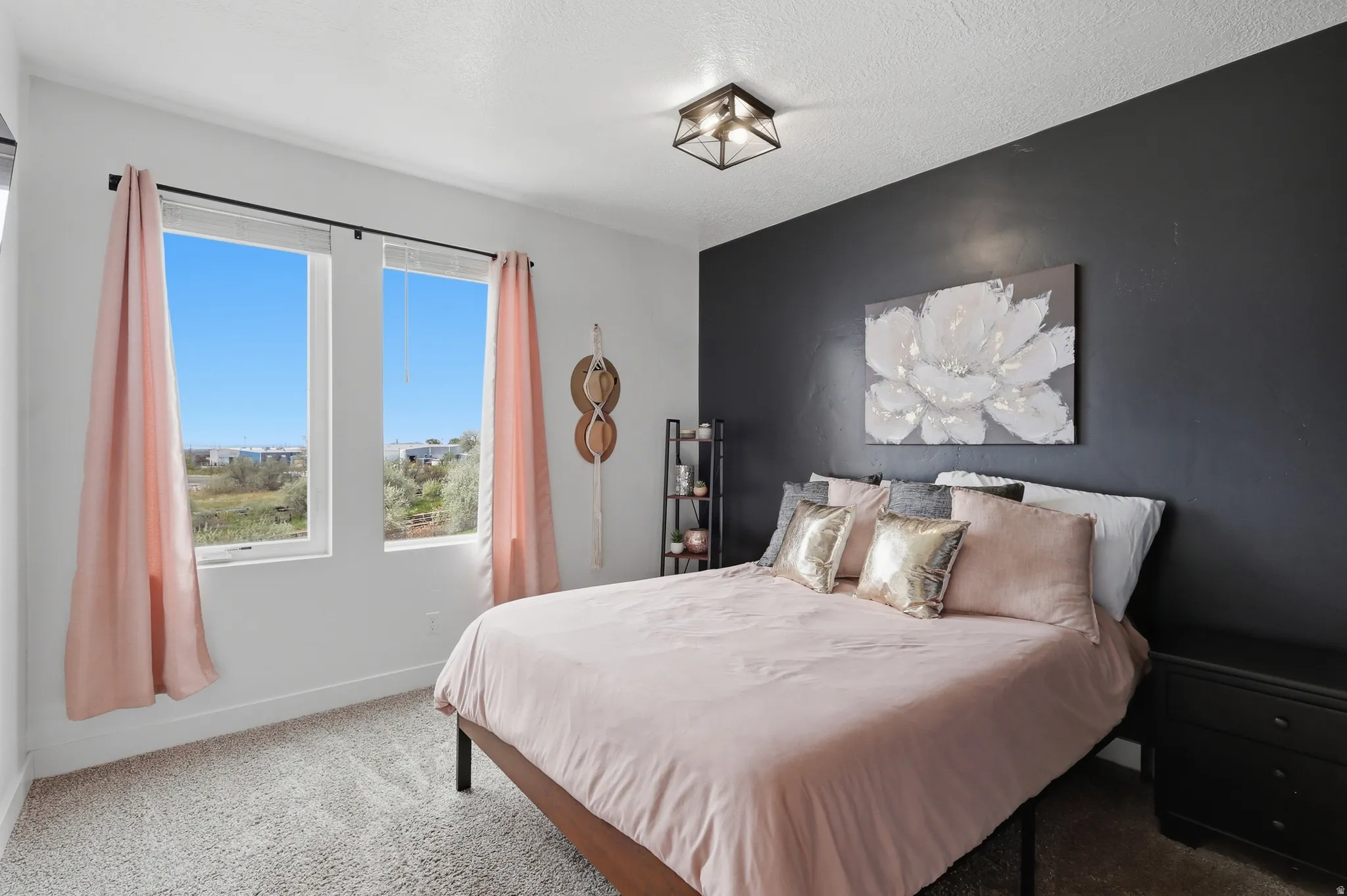 Bedroom with carpet flooring, an accent wall, and a textured ceiling