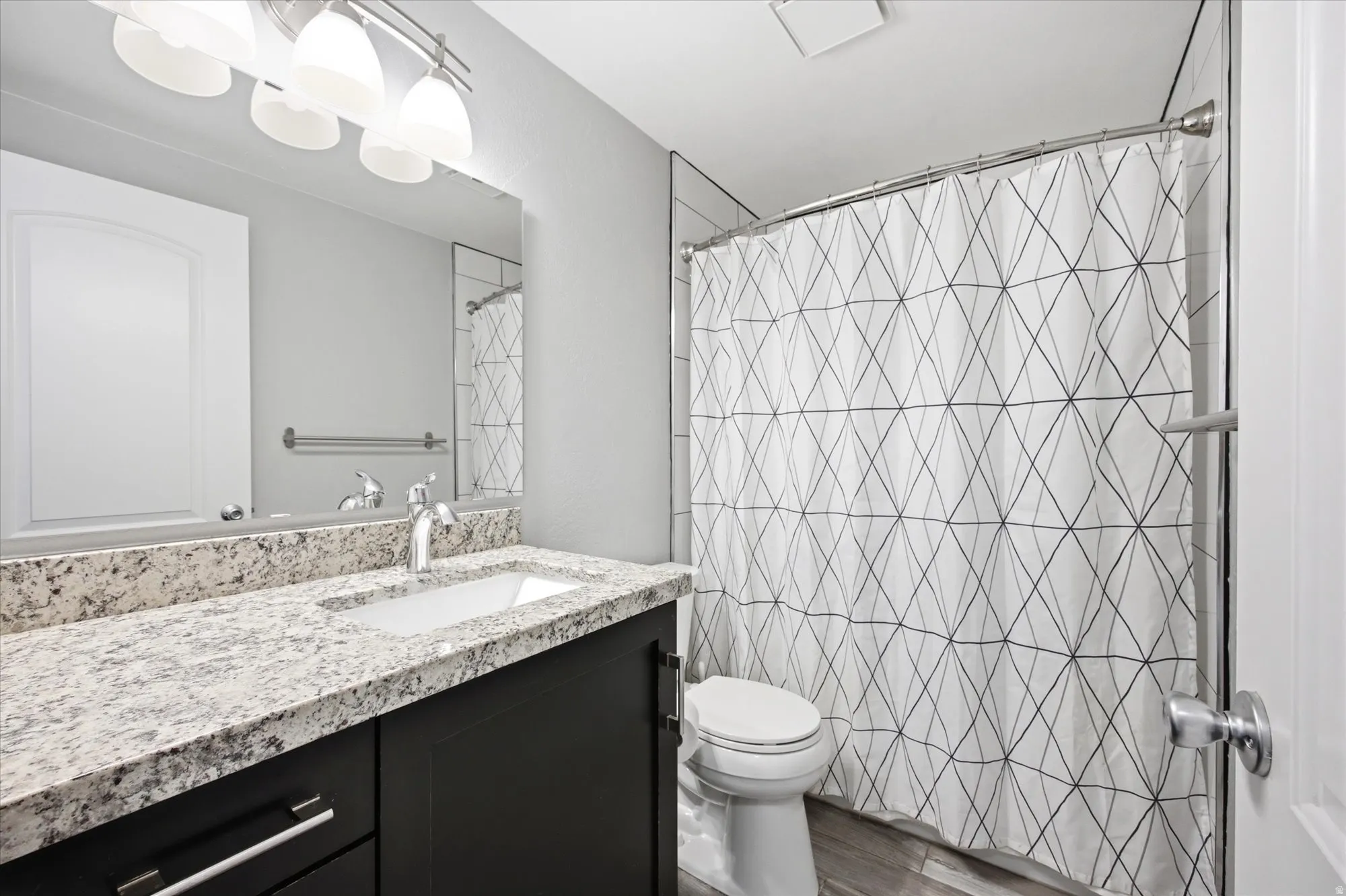 Full bathroom with vanity, a shower with shower curtain, and dark wood-type flooring