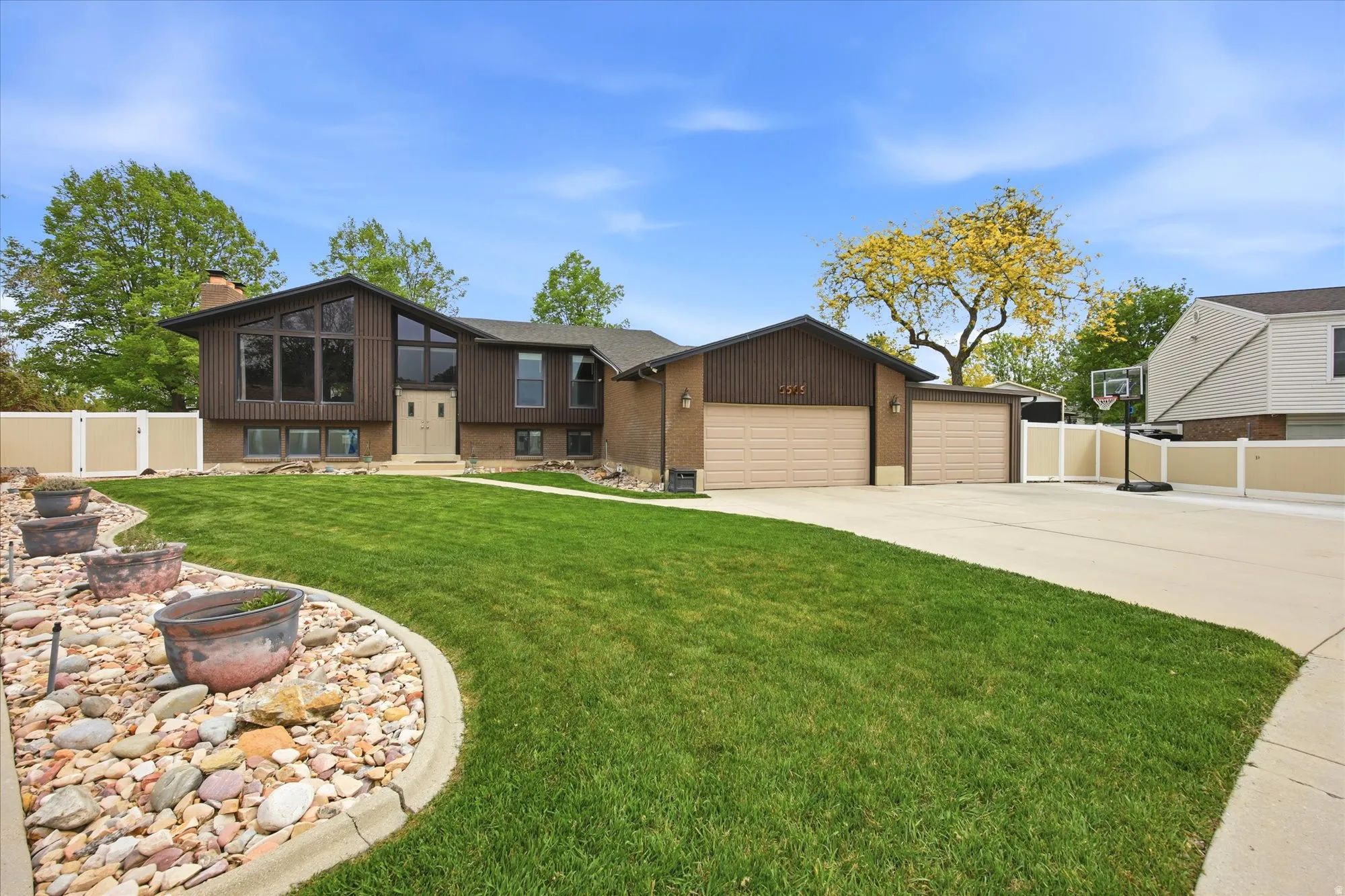 View of front facade with brick siding, an attached garage, driveway, a chimney, and a sunroom