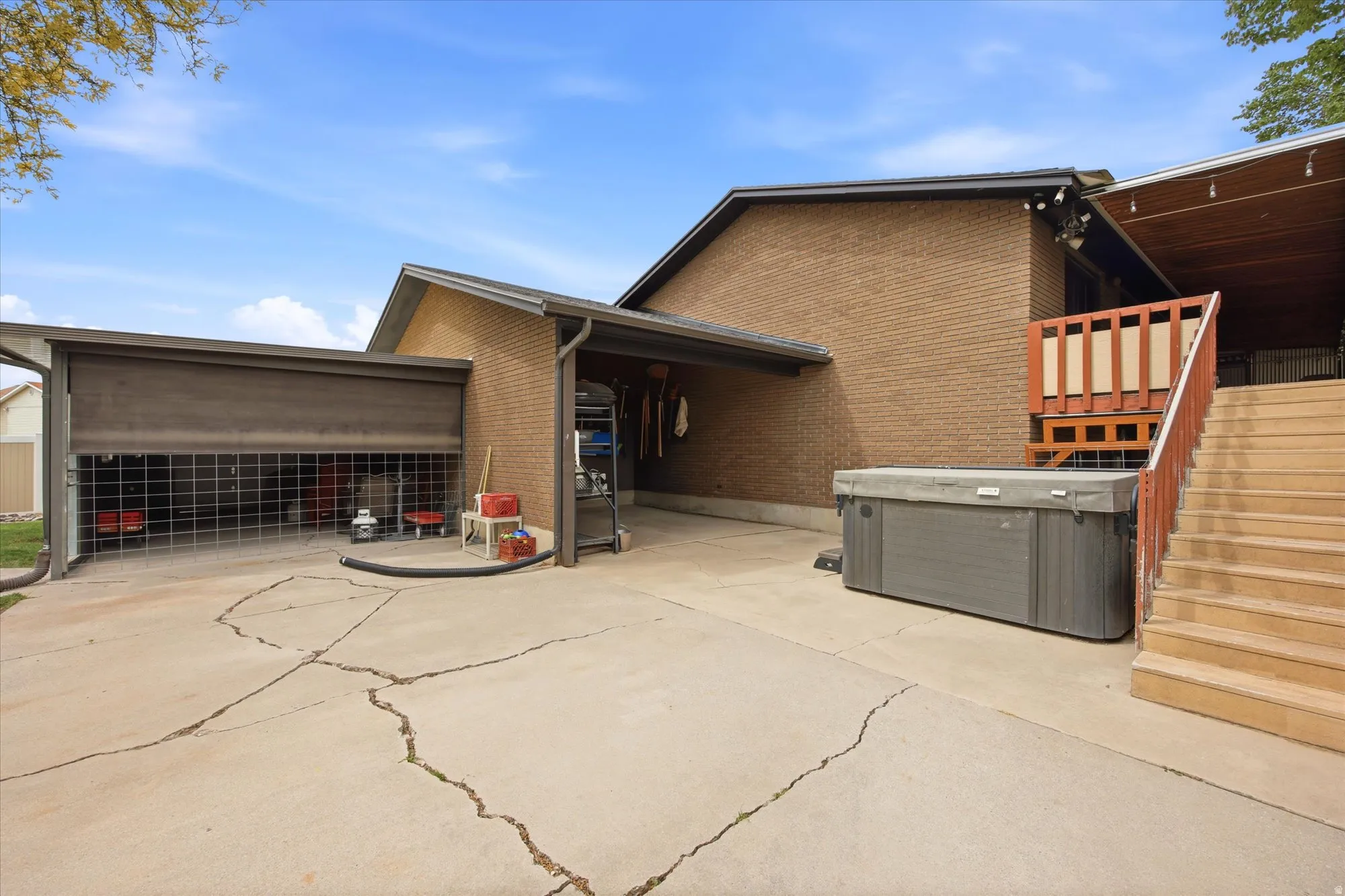 View of side of property with a patio area, brick siding, and a hot tub