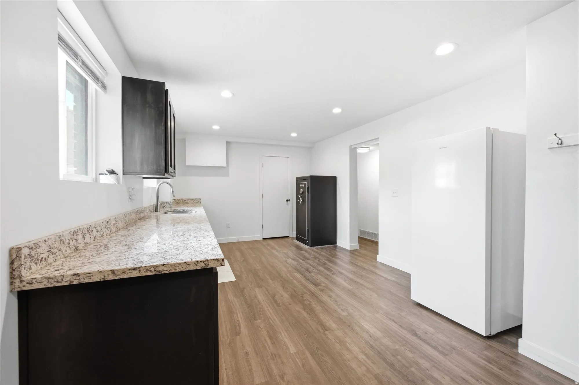 Kitchen with freestanding refrigerator, light wood-type flooring, light stone counters, and recessed lighting
