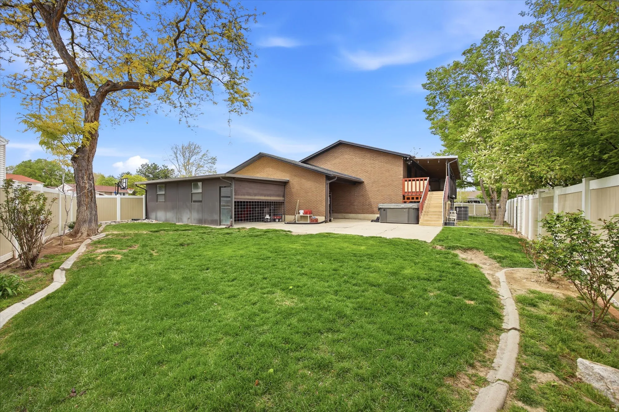 Rear view of property with a fenced backyard, brick siding, and a patio area