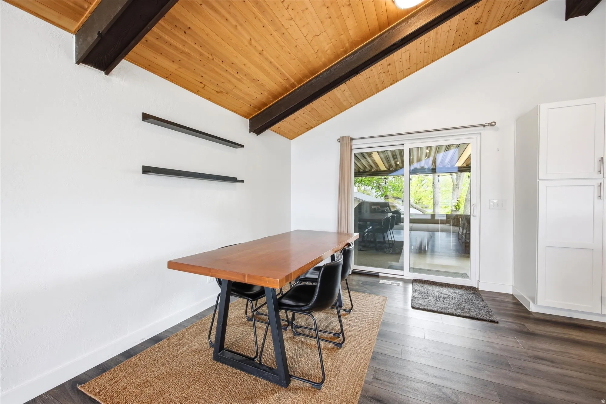 Dining space featuring a high wooden beamed ceiling and dark wood-style flooring