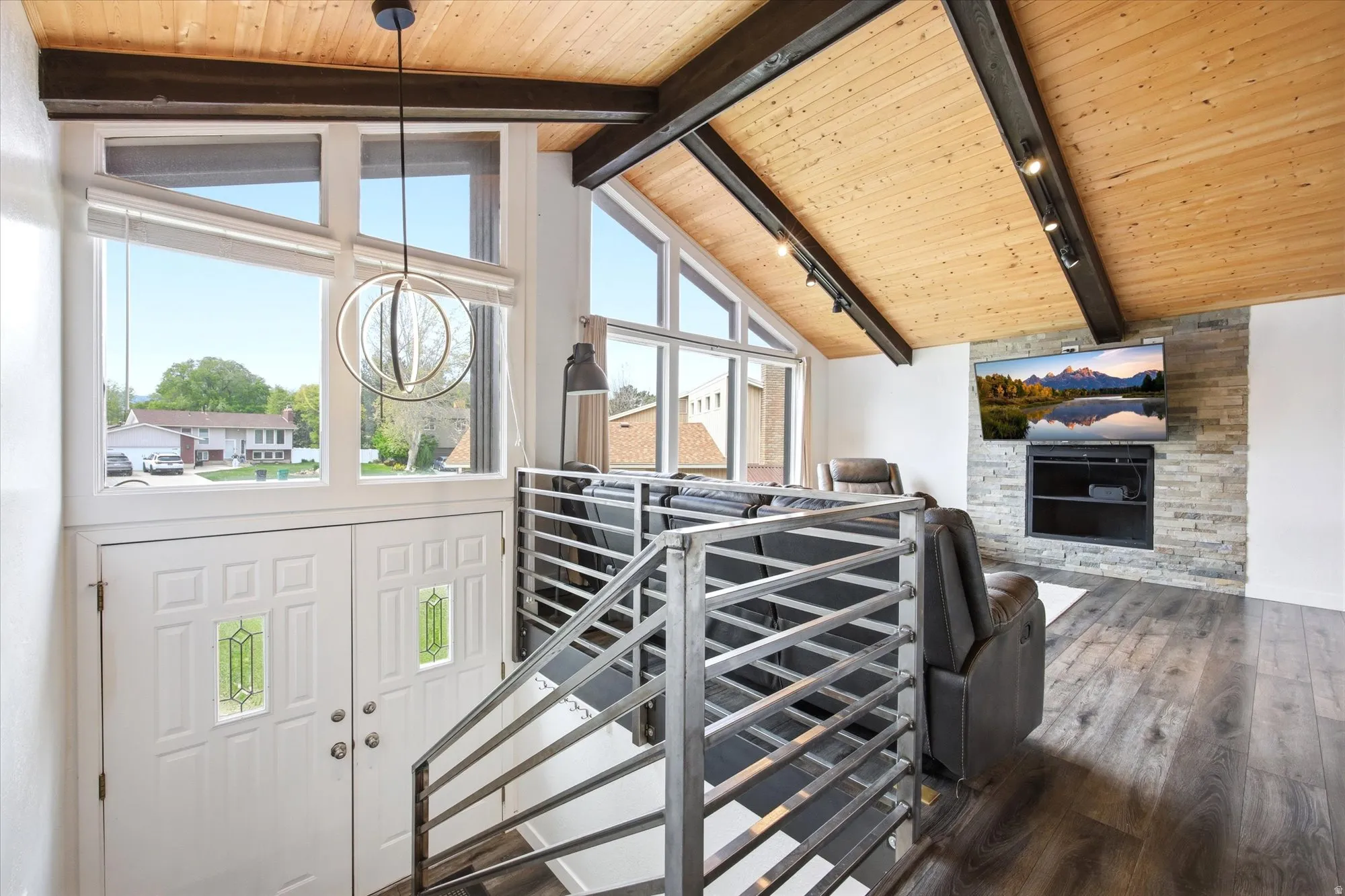 Stairs featuring hardwood / wood-style floors, a stone fireplace, a high wood beamed ceiling, and suspended lighting