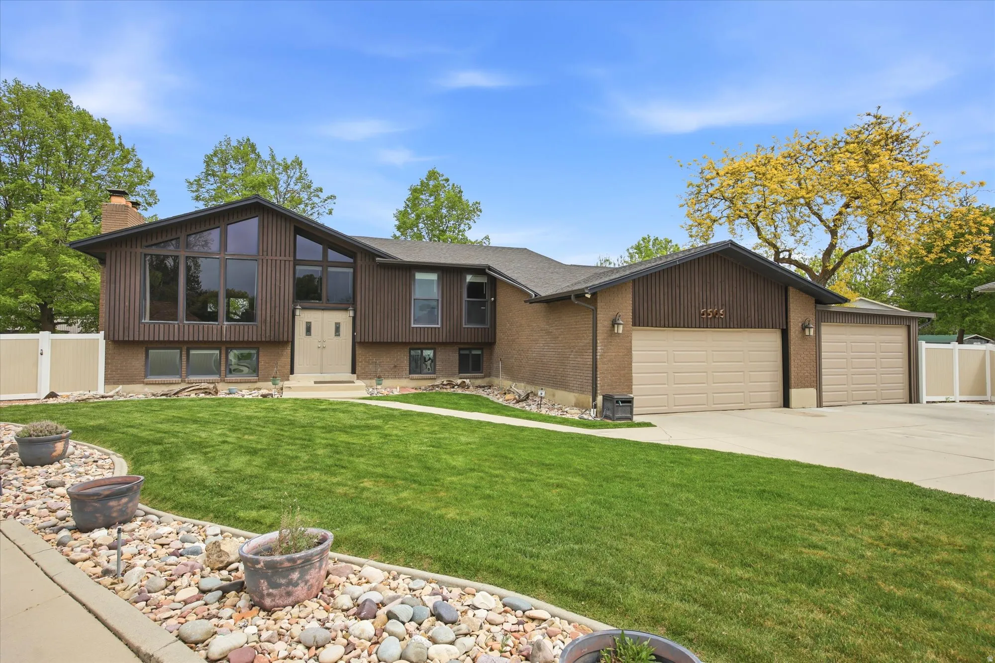 View of front of home with a garage, brick siding, concrete driveway, a chimney, and entry steps