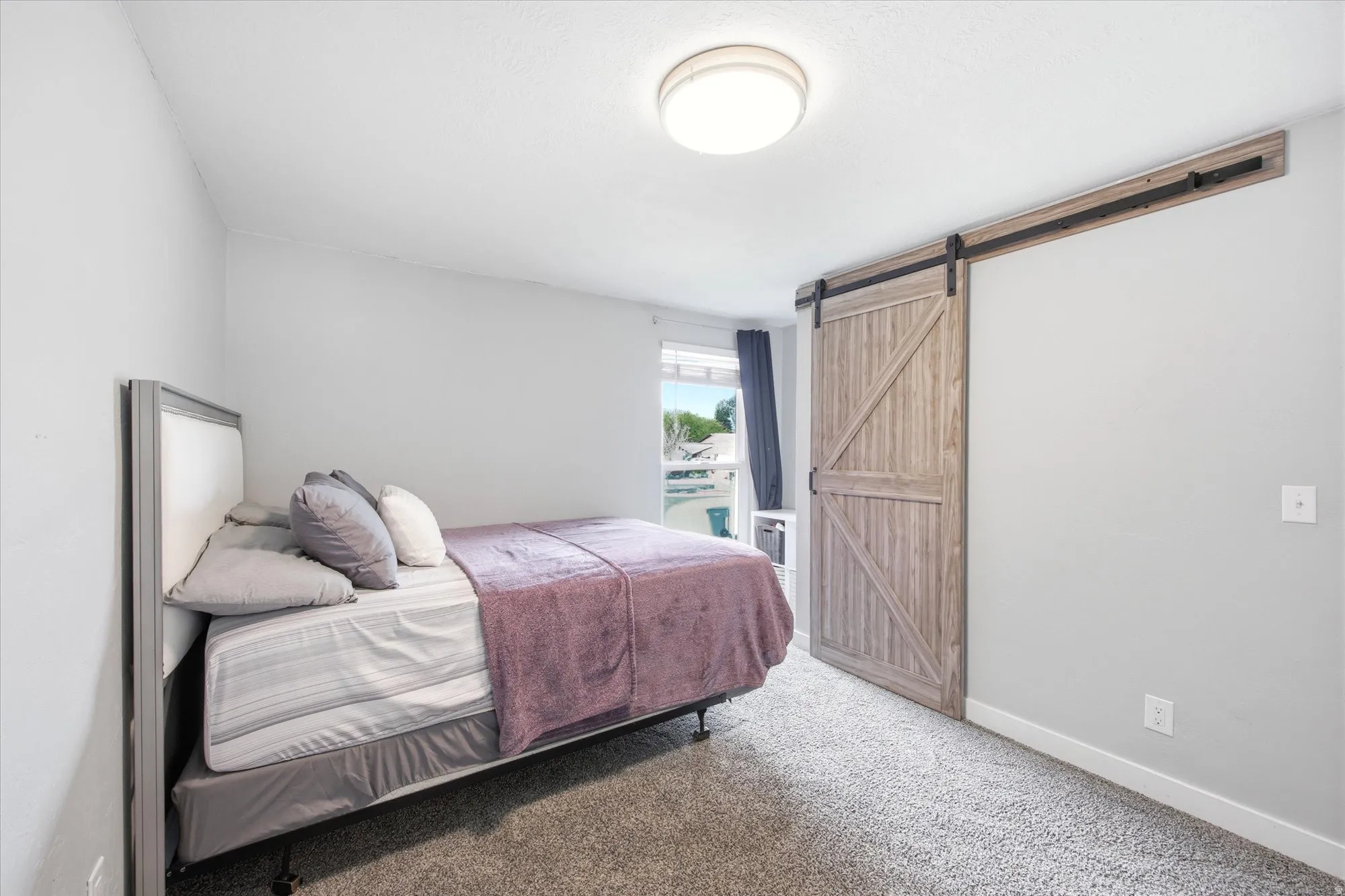 Bedroom with a barn door and light carpet