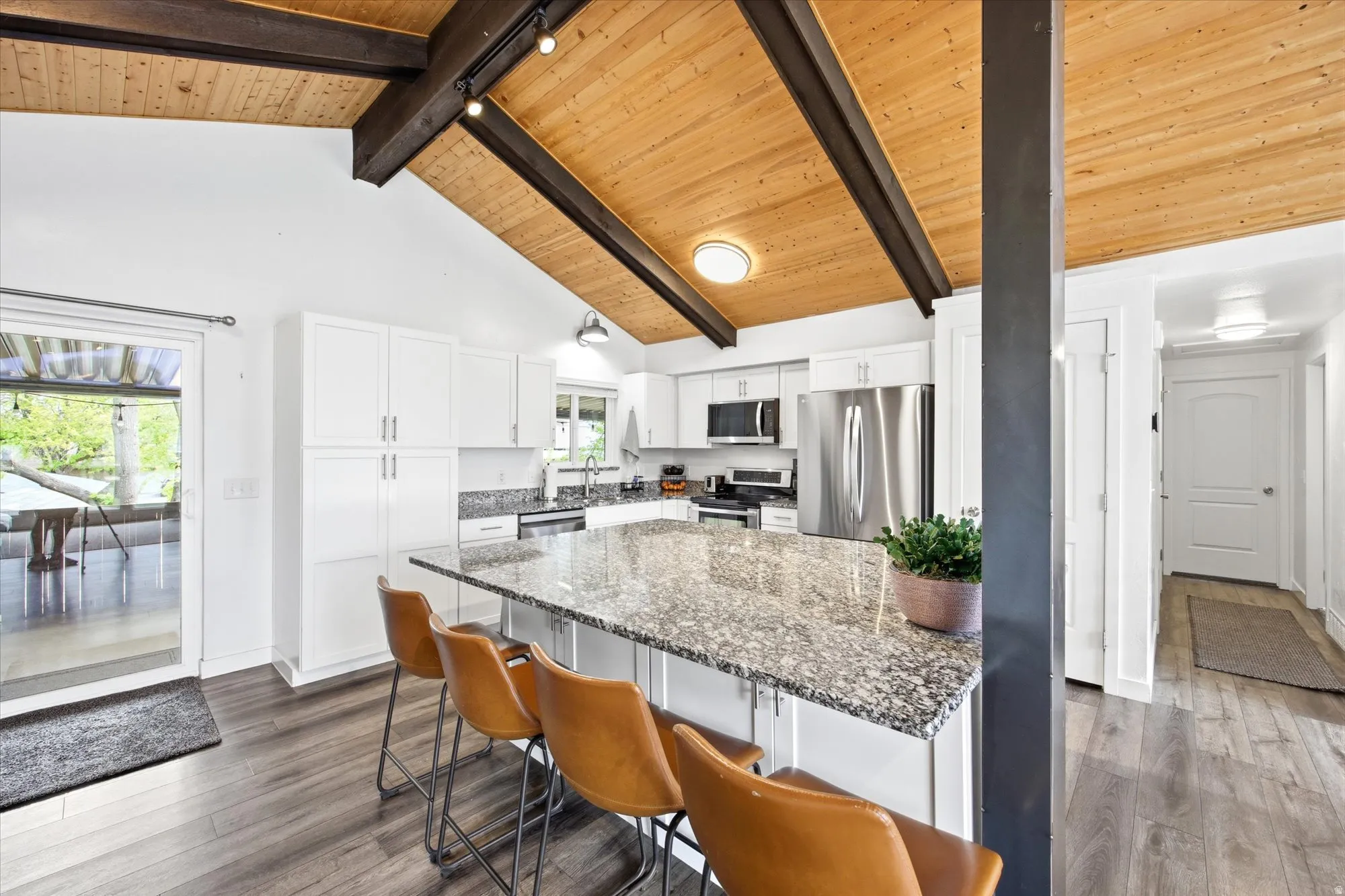 Kitchen with dark wood finished floors, dark stone counters, a center island, a kitchen bar, and stainless steel appliances