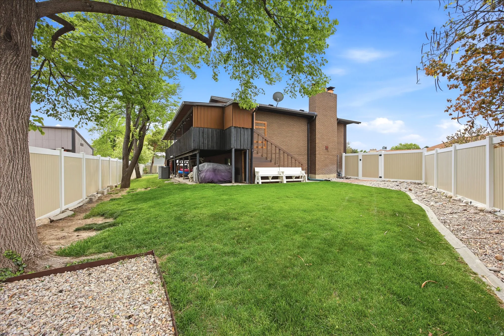 Rear view of property featuring a fenced backyard, a gate, a chimney, and brick siding