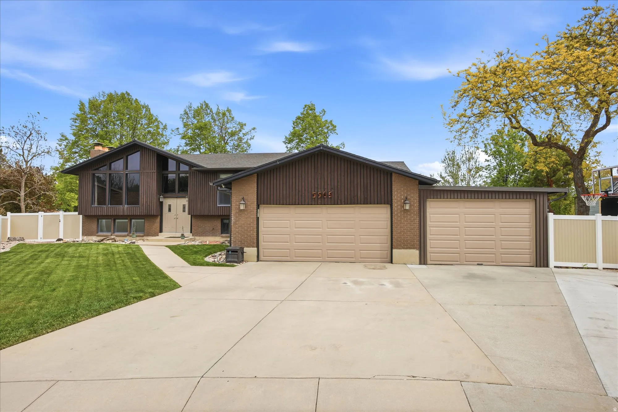 View of front of home featuring brick siding, a garage, concrete driveway, and a chimney