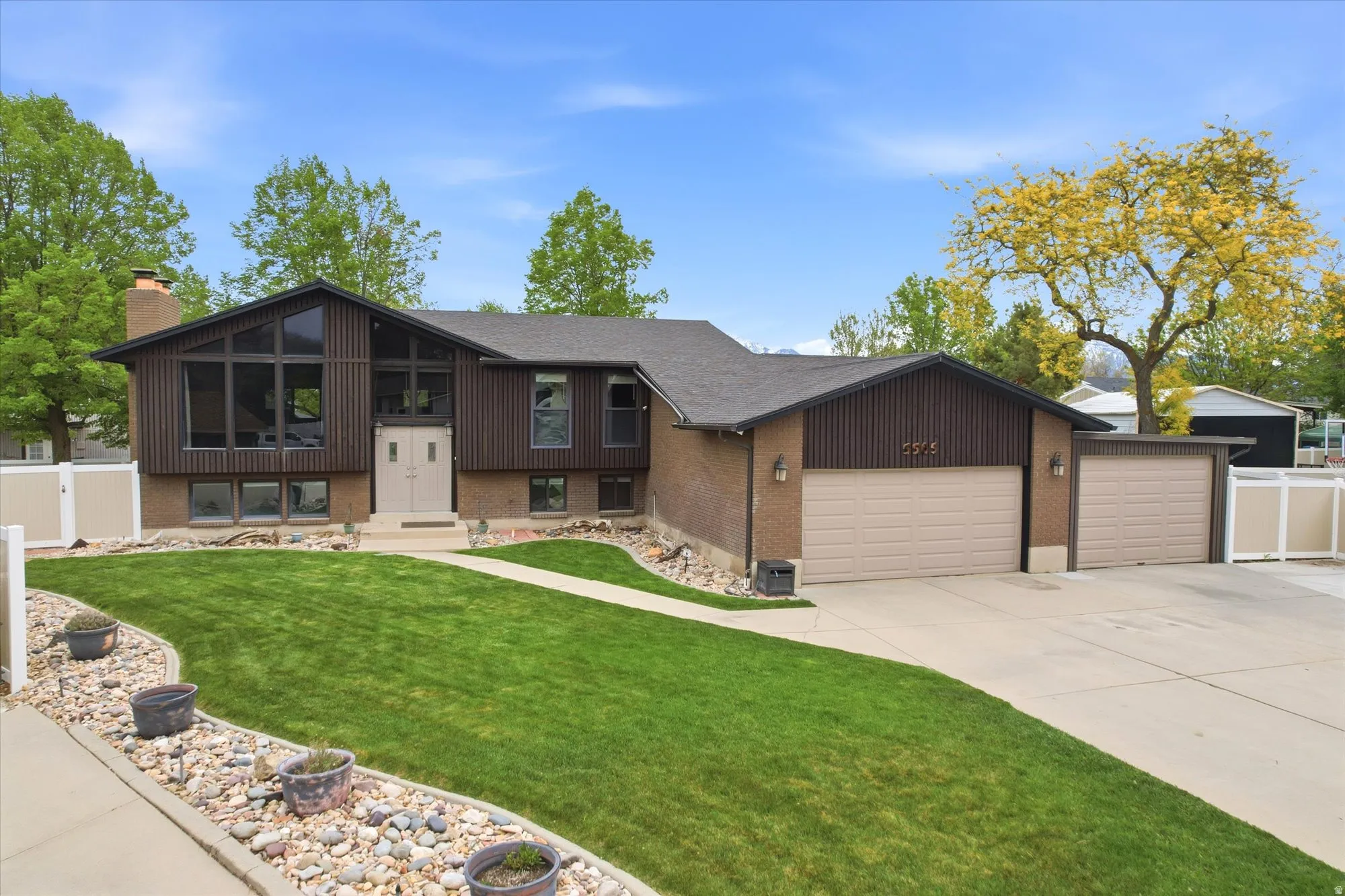View of front of home featuring brick siding, an attached garage, concrete driveway, and a chimney