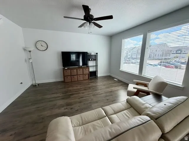 Living area with dark wood-style flooring and a ceiling fan