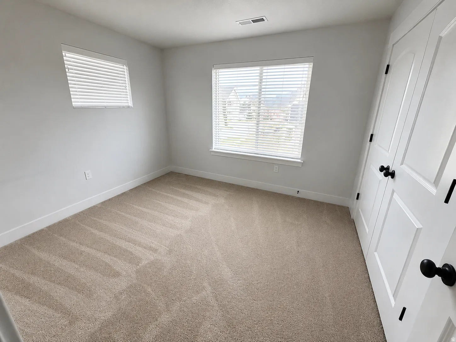 Neutral tone-on-tone carpeting, white baseboards, and white walls create a versatile interior