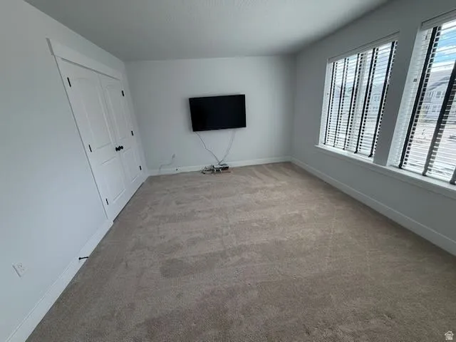 Unfurnished living room featuring baseboards and light colored carpet