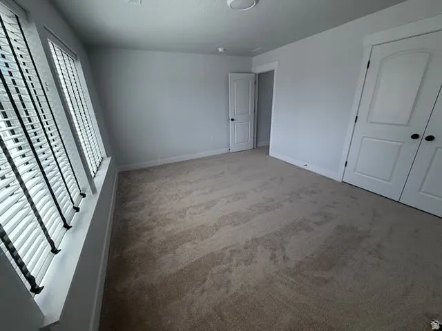 Unfurnished bedroom featuring light colored carpet and baseboards