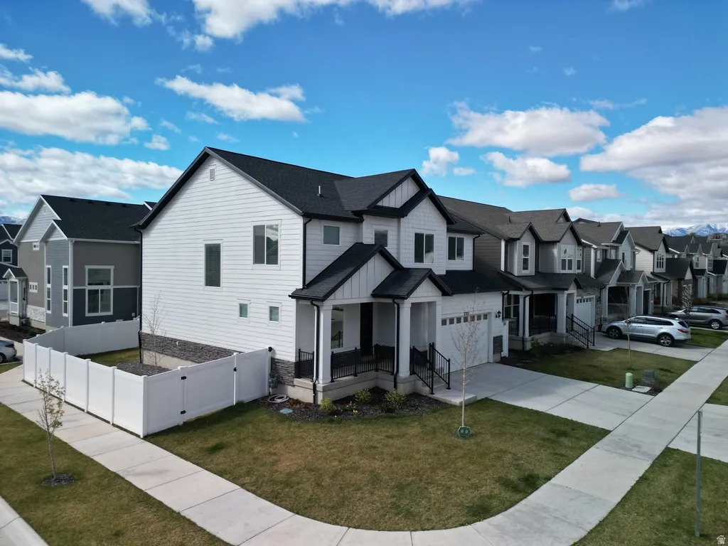 Modern inspired farmhouse with board and batten siding, a residential view, driveway, a front yard, and covered porch