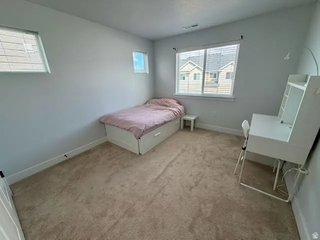 Bedroom with baseboards and light colored carpet