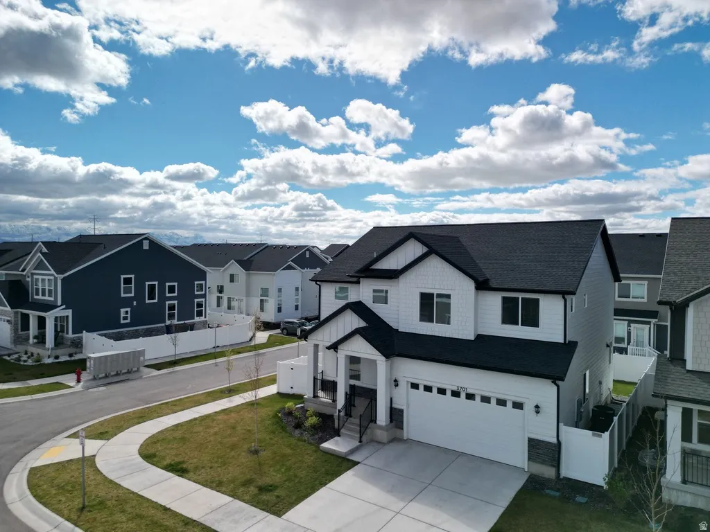 View of front facade featuring board and batten siding, a residential view, driveway, a garage, and roof with shingles