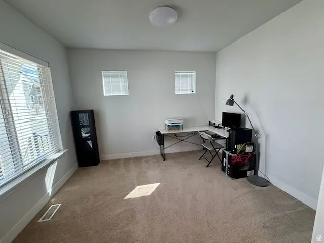 Home office with light carpet and baseboards
