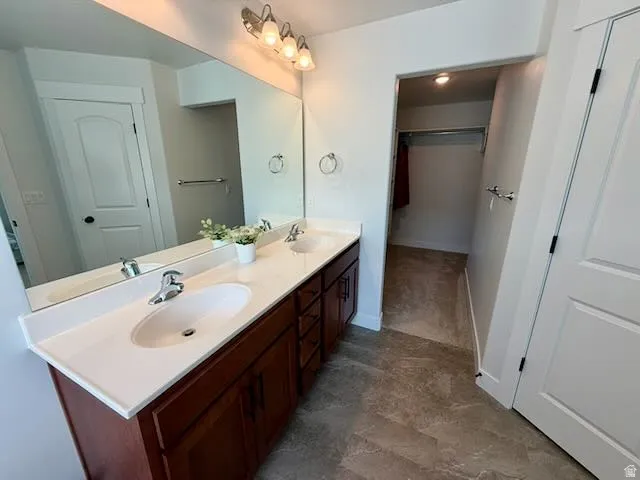 Full bath featuring double vanity and a spacious closet