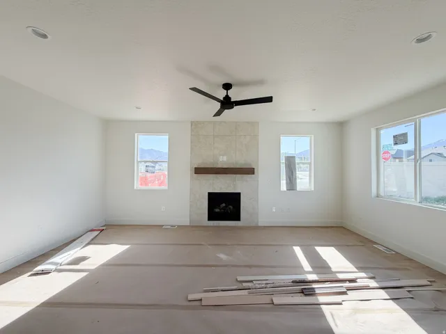 Living space featuring a tile-surround fireplace with a wood mantel, recessed lighting, and a ceiling fan