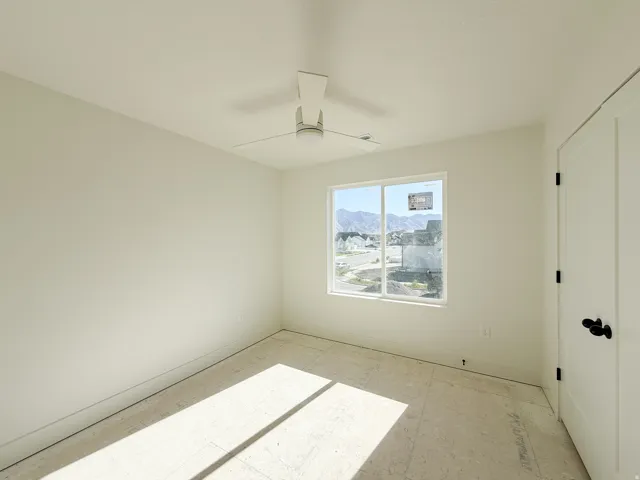 Bright room featuring a large window, a modern ceiling fan, and white walls