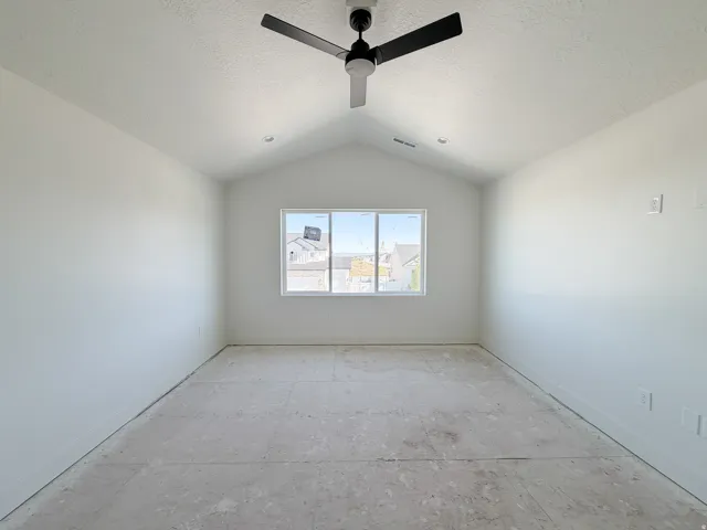 Spacious room featuring vaulted ceilings, a contemporary ceiling fan, and a triple-pane window