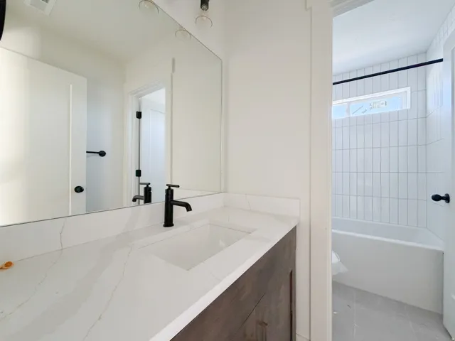 Bathroom featuring a quartz countertop vanity with an integrated rectangular sink and matte black faucet