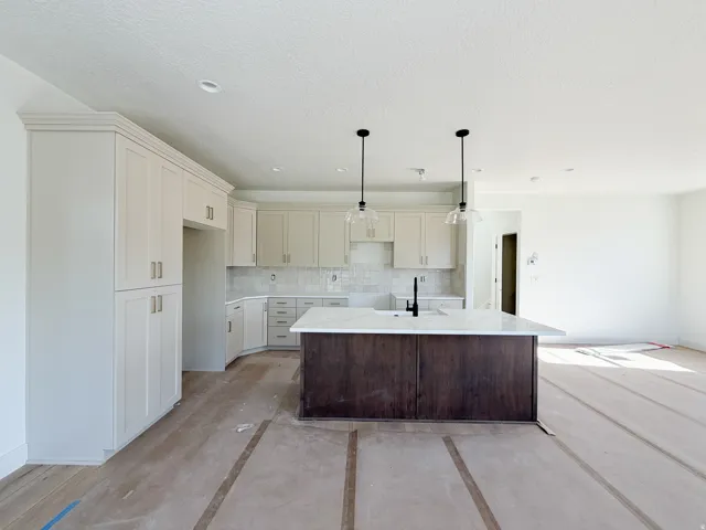 Expansive kitchen featuring a two-tone island with a light-toned countertop, pendant lighting, shaker-style cabinetry, and a subway tile backsplash