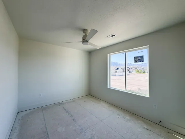 Interior room featuring a large window, a ceiling fan, baseboard trim, and a serene mountain backdrop