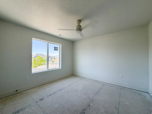 Spacious room featuring a large window, light-colored walls, white trim, and a ceiling fan