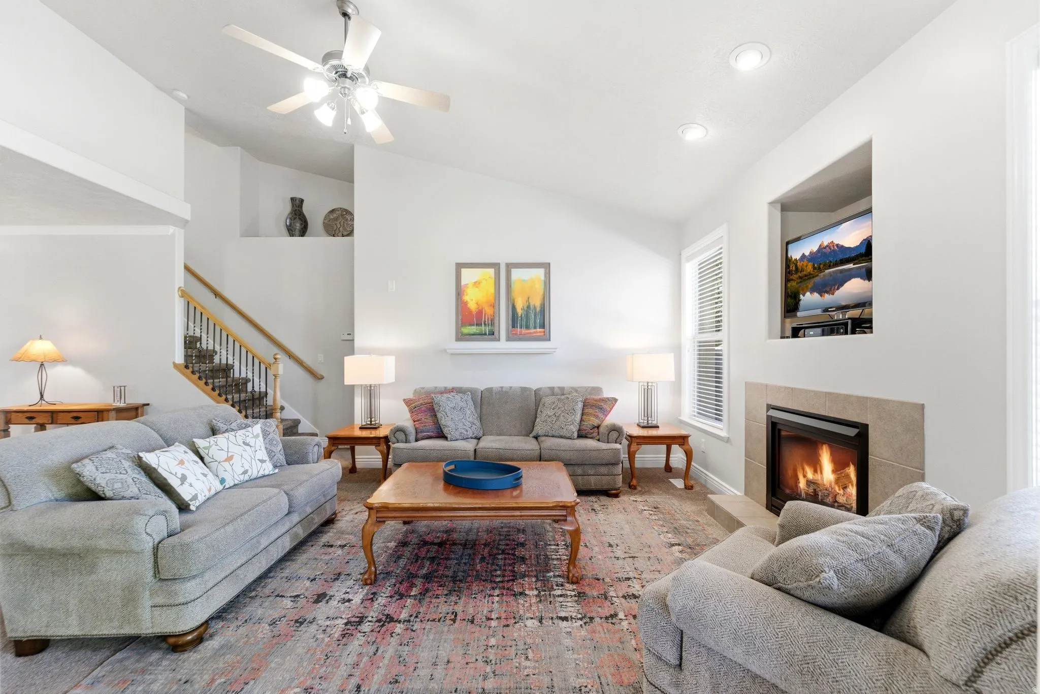 Living area with ceiling fan, a tile fireplace, and vaulted ceiling