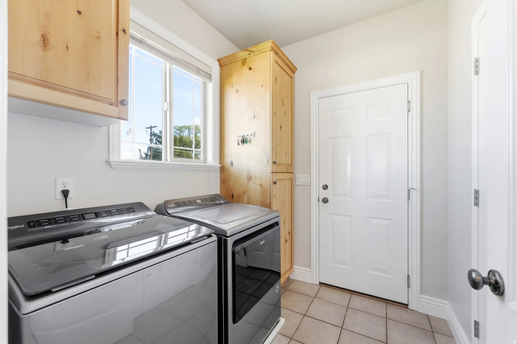 Laundry room with light tile patterned floors, independent washer and dryer, and cabinet space