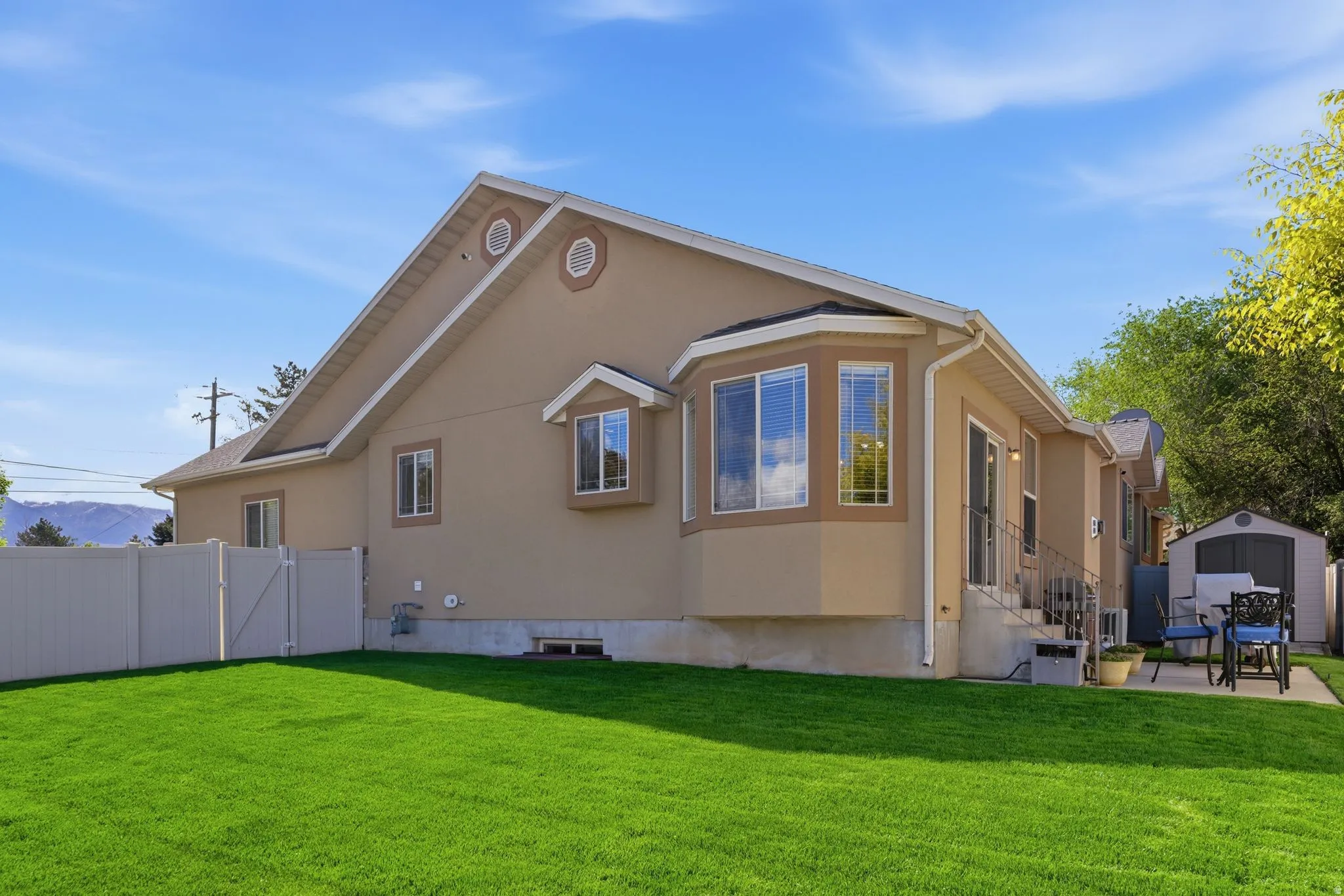Back of house with stucco siding, a storage shed, and a patio