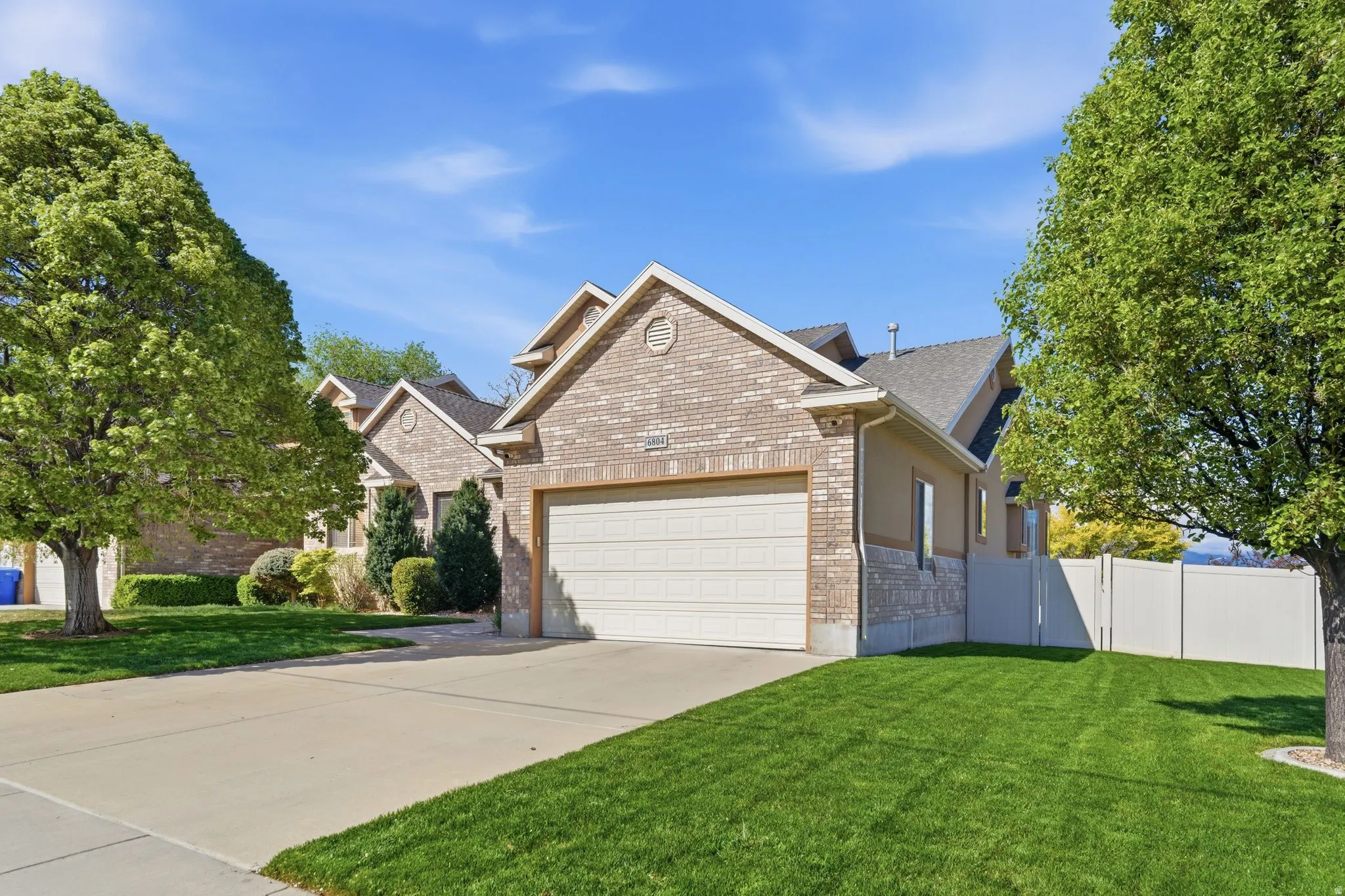 View of front of property with a garage, driveway, brick siding, and roof with shingles