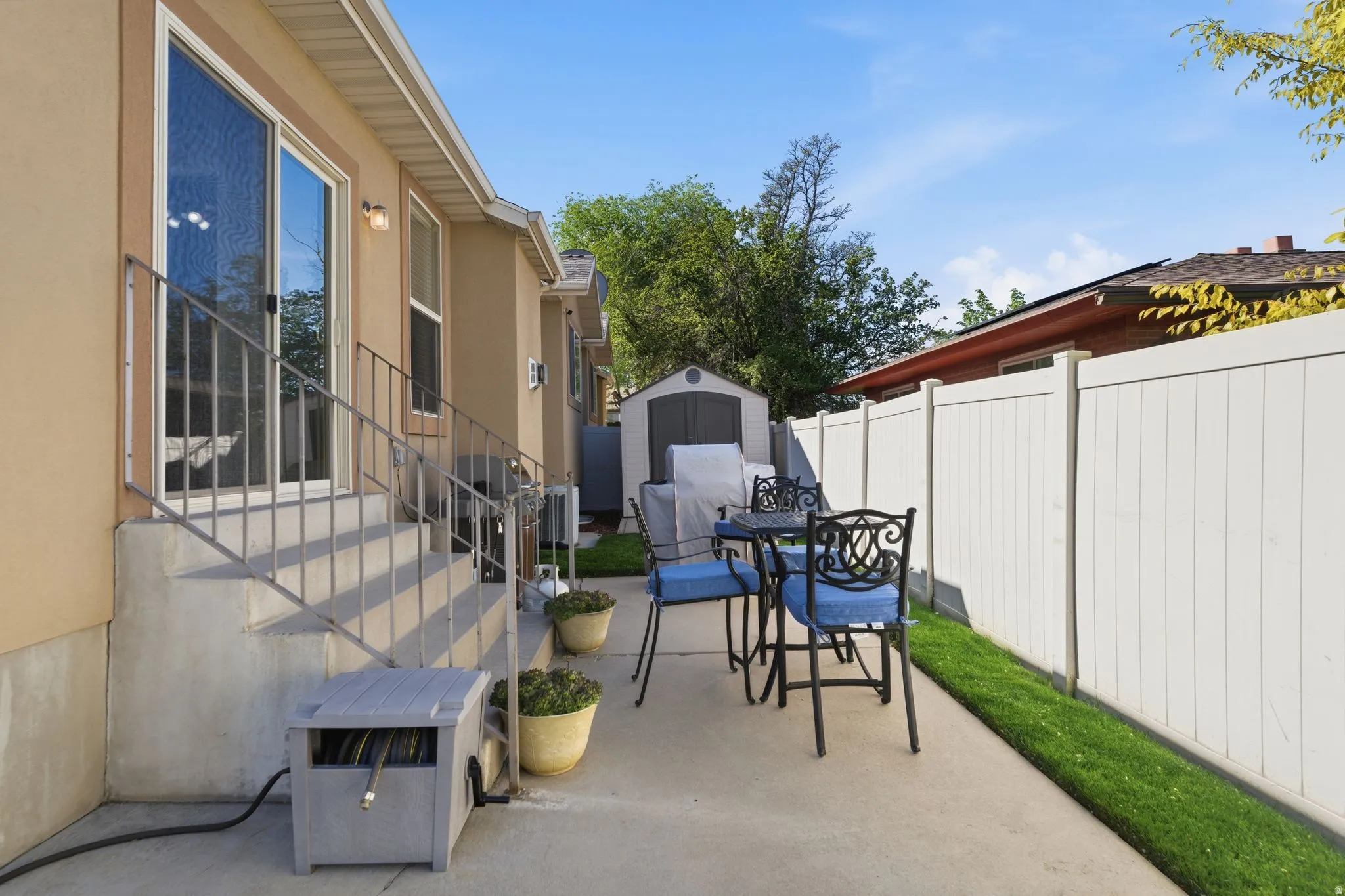 Fenced backyard with a storage unit, outdoor dining space, a patio area, and entry steps