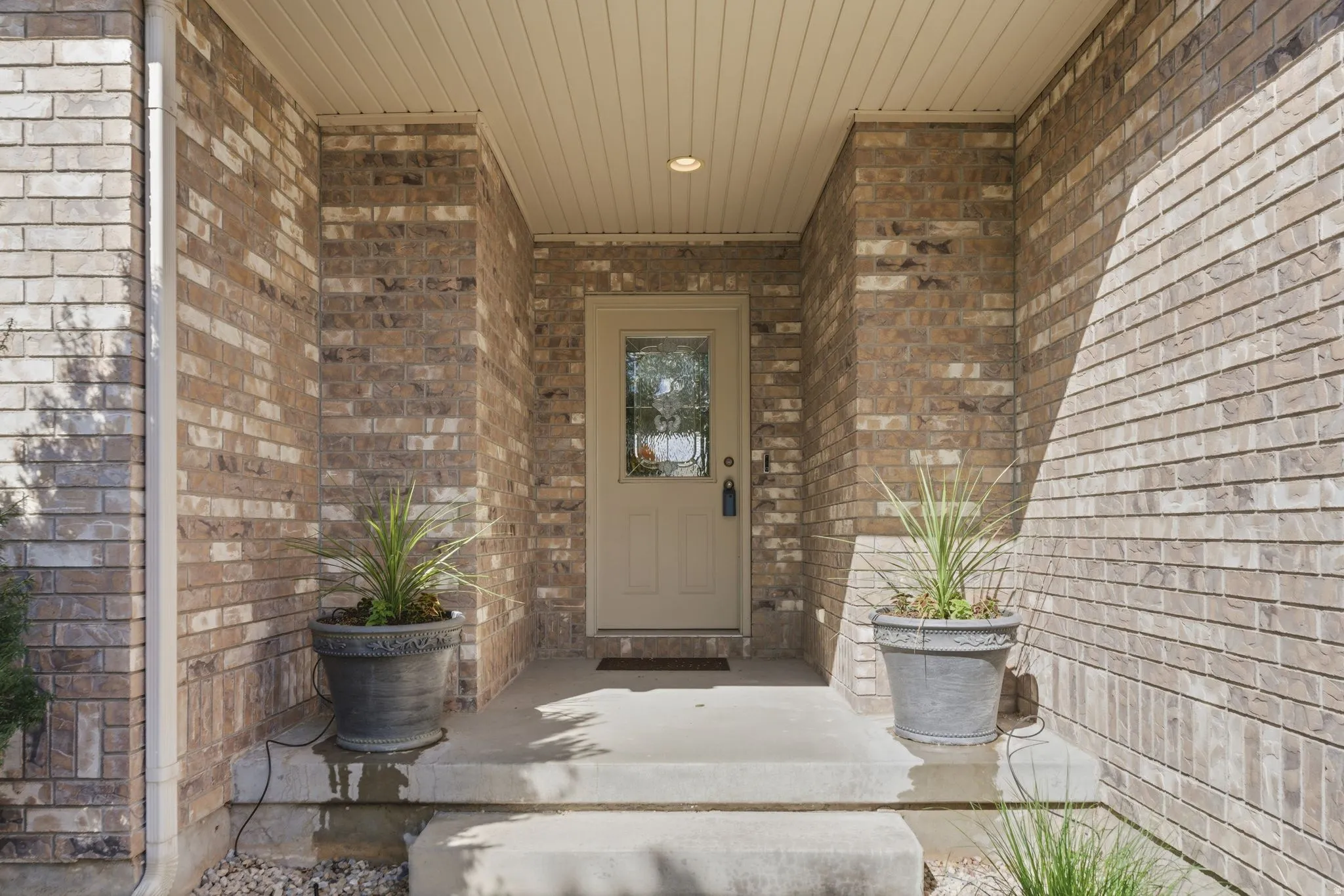 Doorway to property featuring brick siding and covered porch