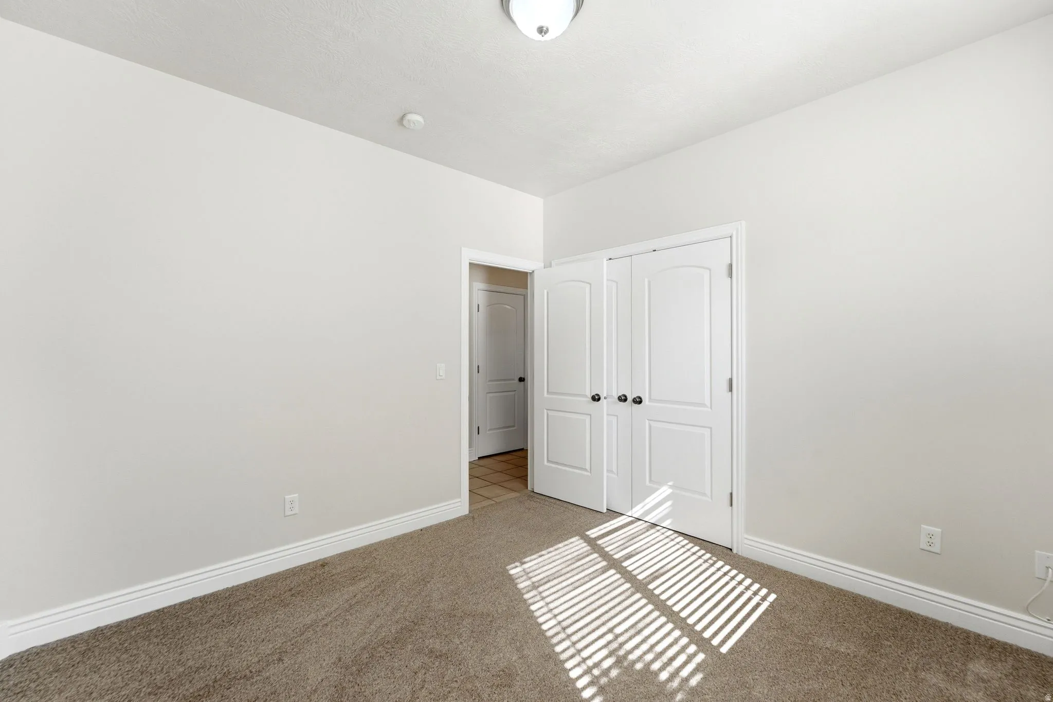 Unfurnished bedroom featuring a closet and light colored carpet