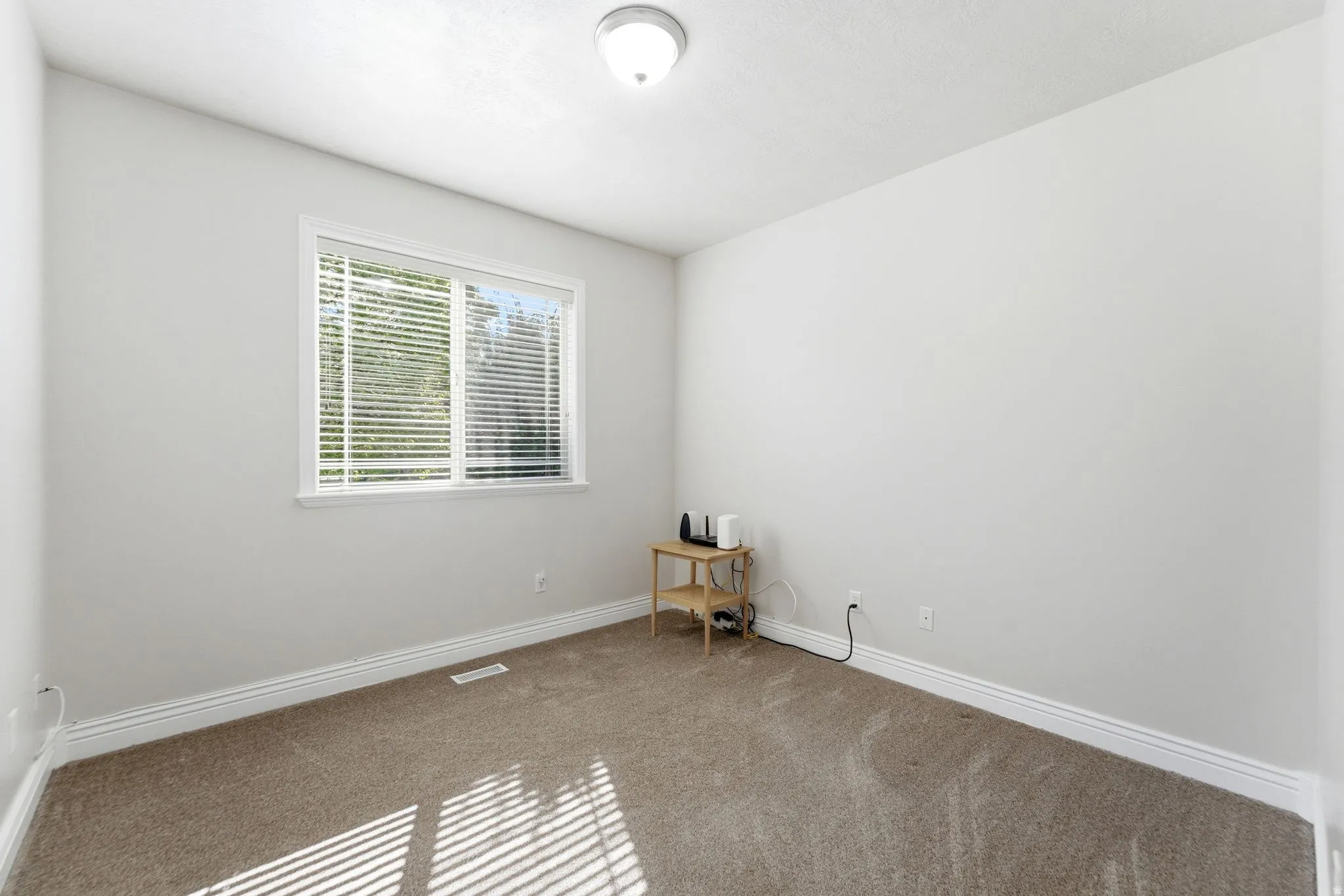 Carpeted spare room featuring baseboards
