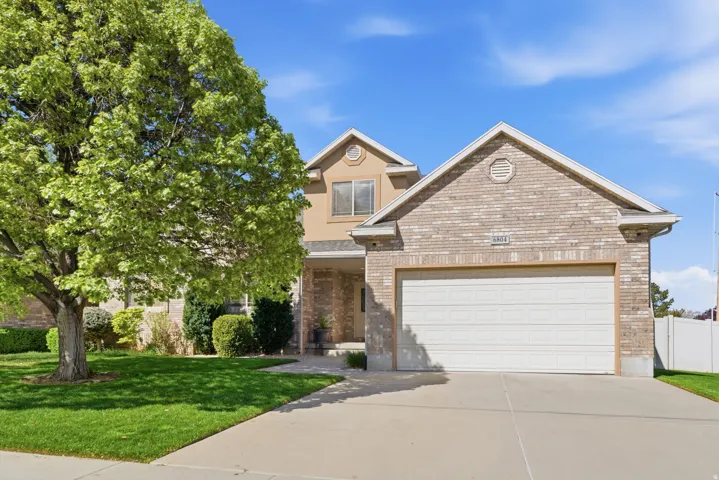 View of front of property with an attached garage, driveway, brick siding, and a porch