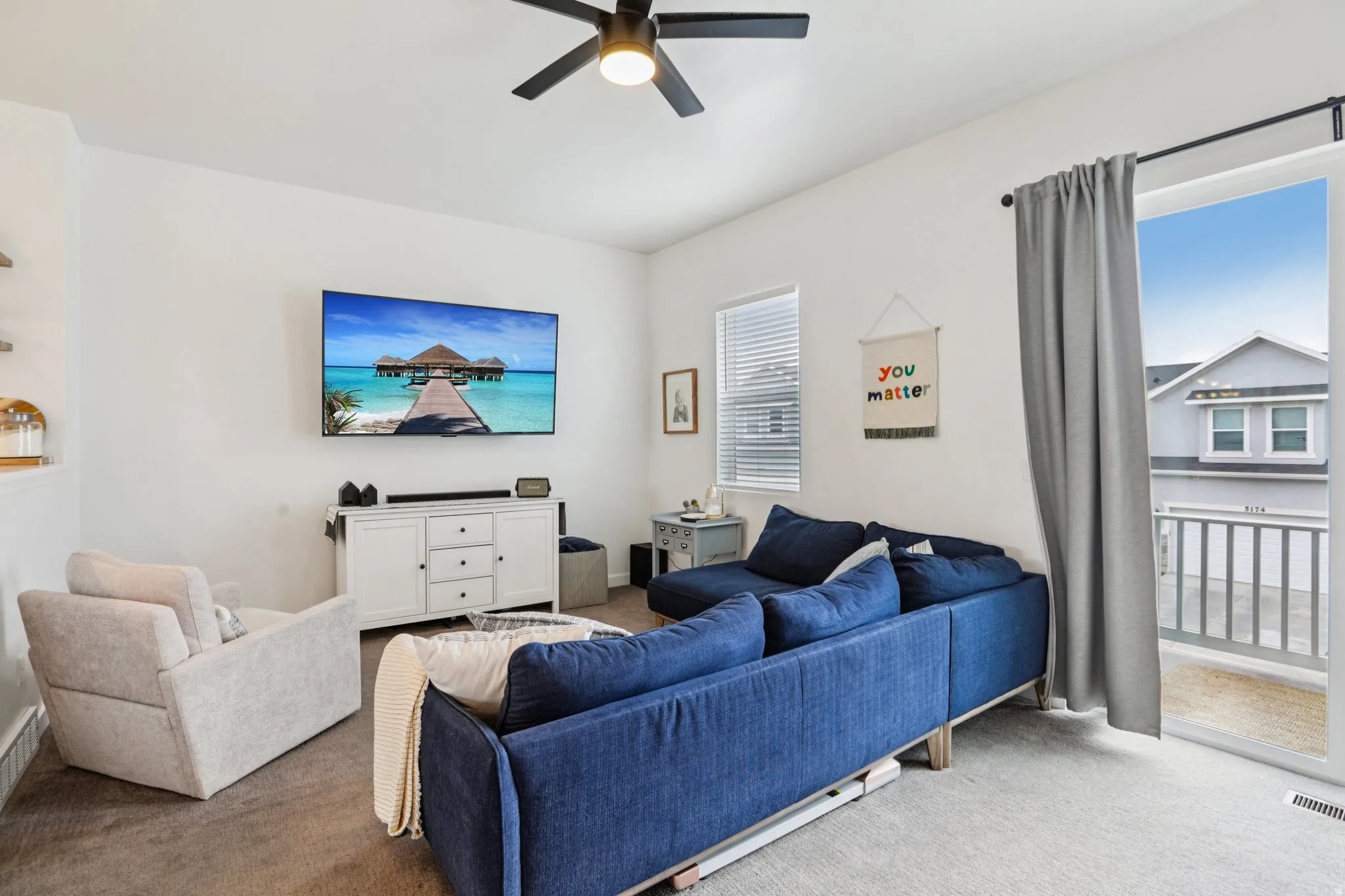 Carpeted living area with ceiling fan
