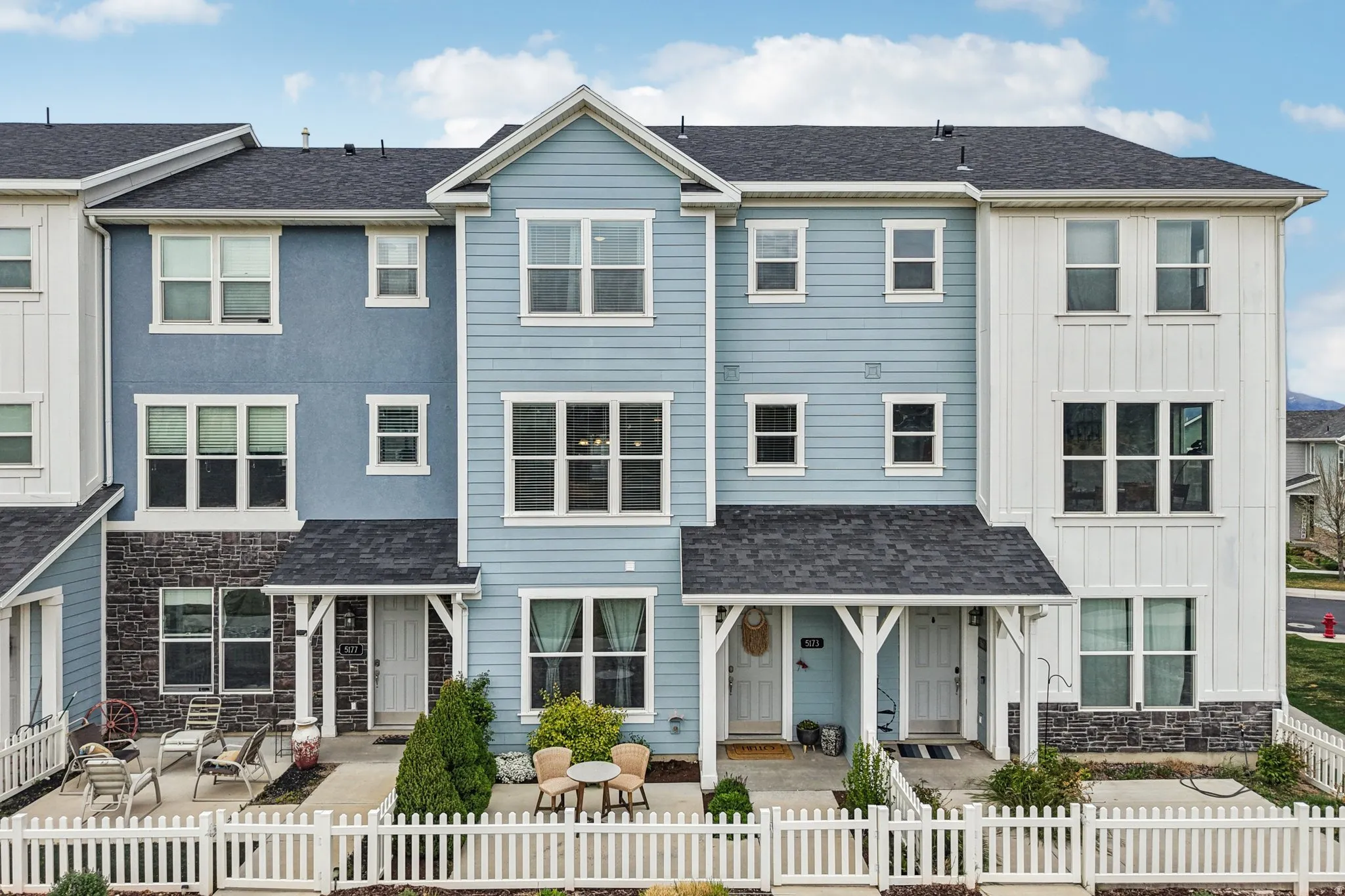 View of front of house with board and batten siding, stone siding, a fenced front yard, and a shingled roof