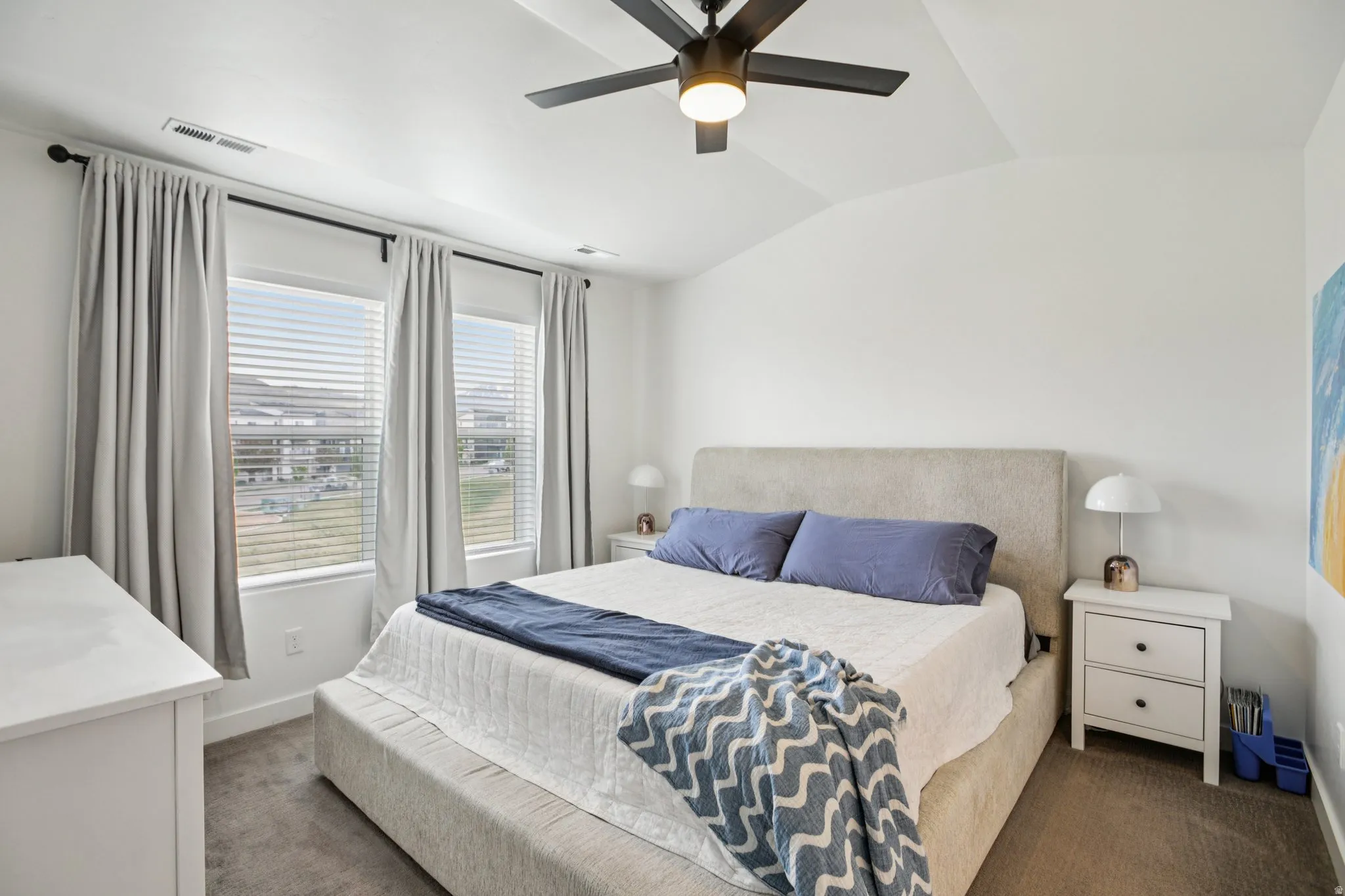 Bedroom with dark colored carpet, lofted ceiling, and a ceiling fan