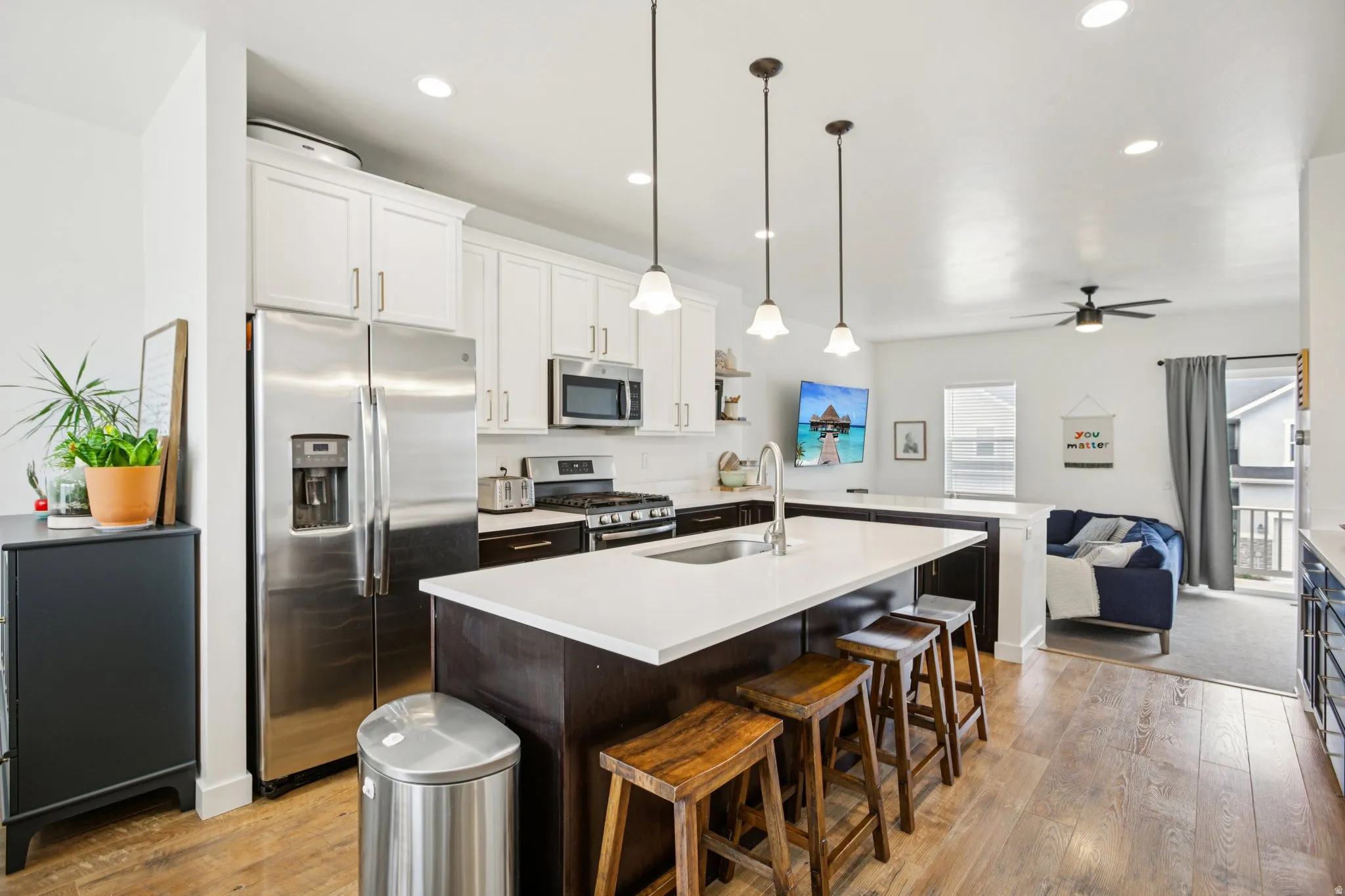 Kitchen with stainless steel appliances, a breakfast bar area, light wood-type flooring, open floor plan, and dual tone cabinets