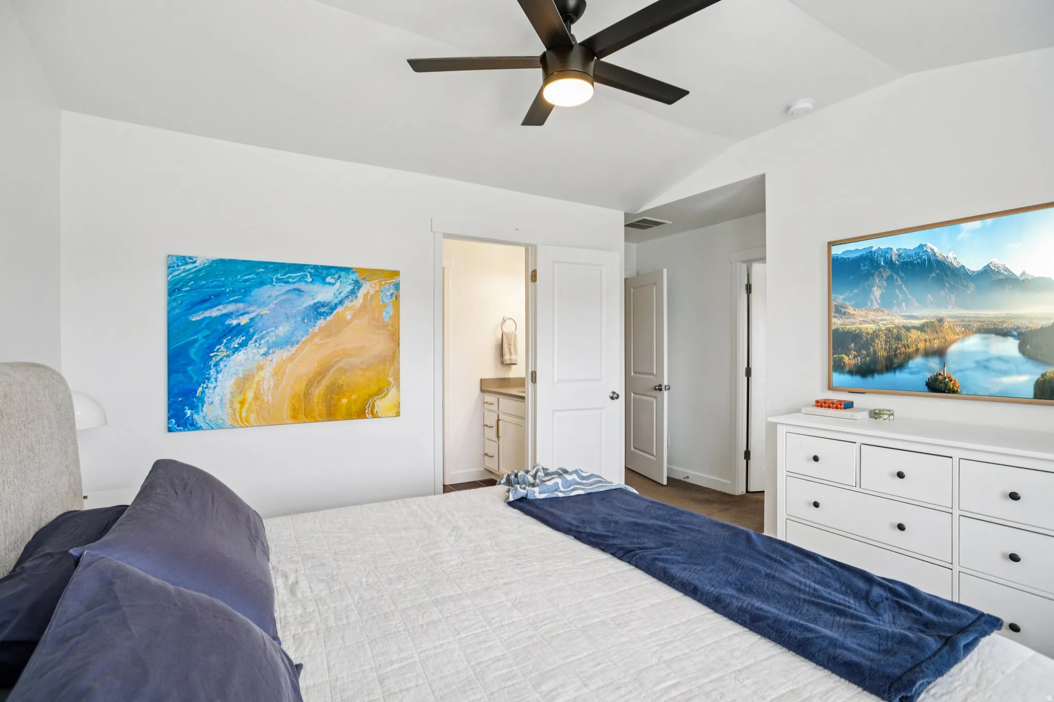 Bedroom with lofted ceiling, a ceiling fan, and connected bathroom