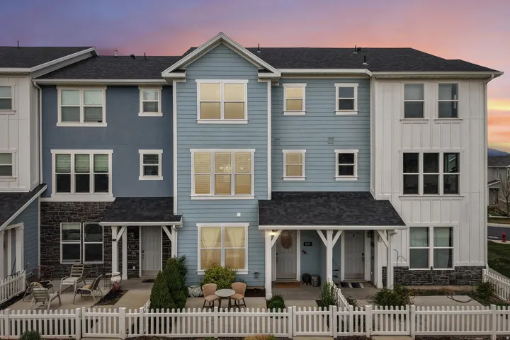 View of front of house with board and batten siding, stone siding, a fenced front yard, and roof with shingles